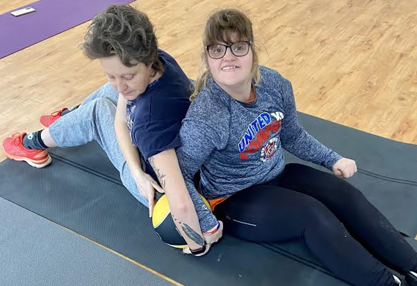 Two young women on mat with ball